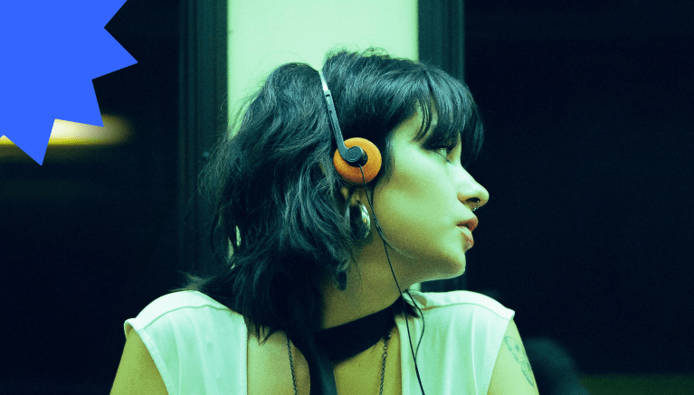 Young woman with black hair and orange headphones looking away inside a dimly lit subway train, evoking a mood of emotional distance or disconnection.